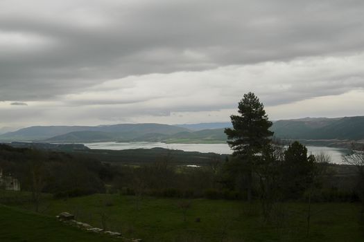 Fountain in a mountain landscape with a lake, Wet and green landscape with clouds in the sky