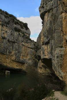 River through steep mountains, Bluish sky with soft white clouds