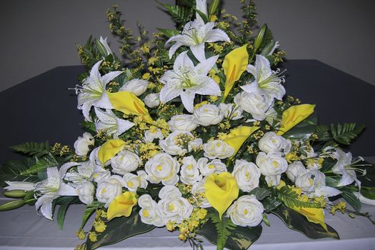 Large bouquet of white and yellow flowers. With green branches on a gray table