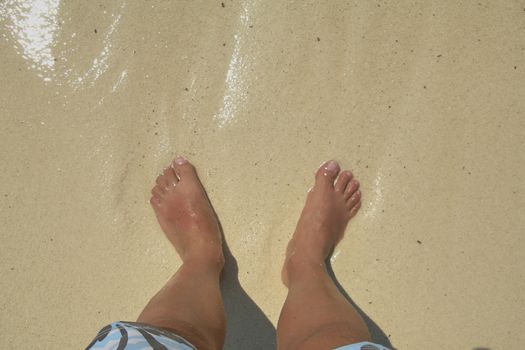 Bare feet in the water on a Caribbean beach, calm and transparent waters