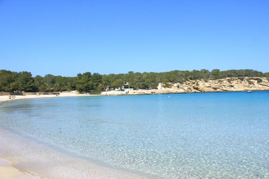 Deserted beach with turquoise waters, bright day, Mountains in the background and bright blue day