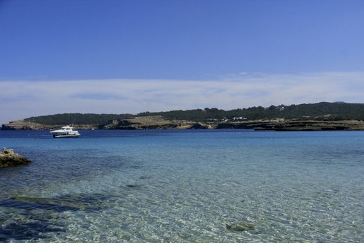 Deserted beach with turquoise waters, bright day, Mountains in the background and bright blue day, two boats sailing