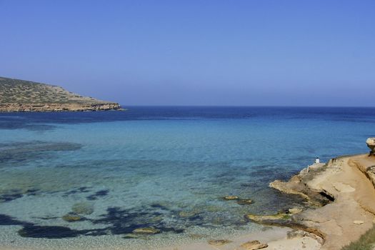 Deserted beach with turquoise waters, bright day, Mountains in the background and bright blue day,