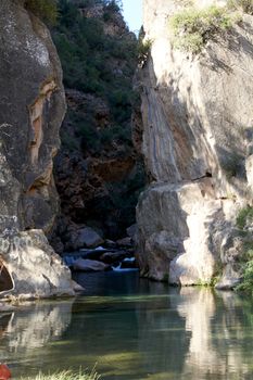 River of calm waters between two mountains, transparent waters, small waterfall