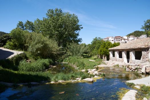 River of calm and transparent waters through the forest, blue sky, building for washing clothes, laundry, old town