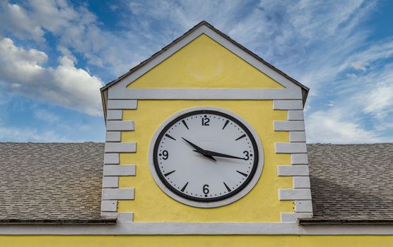 A classic clock on the roofline of a yellow plaster building