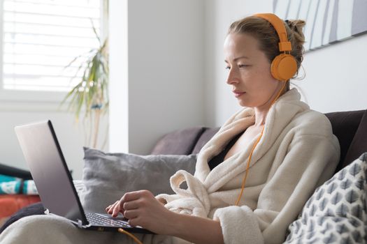 Stay at home and social distancing. Woman in her casual home bathrobe working remotly from her living room. Video chatting using social media with friend, family, business clients or partners.