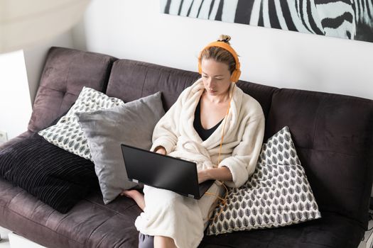 Stay at home and social distancing. Woman in her casual home bathrobe working remotly from her living room. Video chatting using social media with friend, family, business clients or partners.