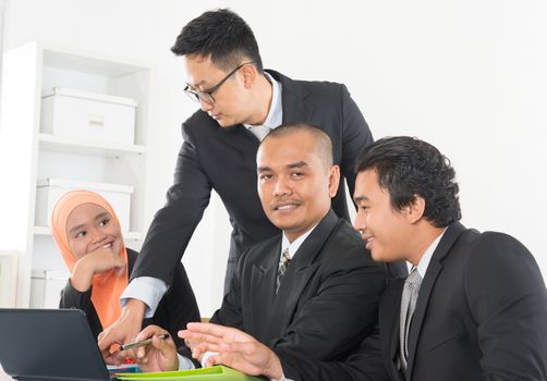 Group of Malaysian businesspeople meeting or having discussion on desk inside office room.