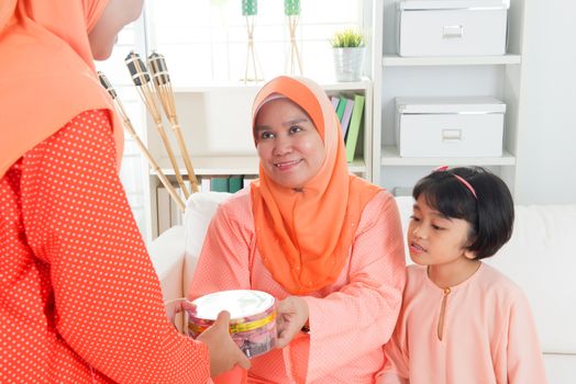 Woman giving elder cookies during Hari Raya. Malay or Malaysian family lifestyle at home.