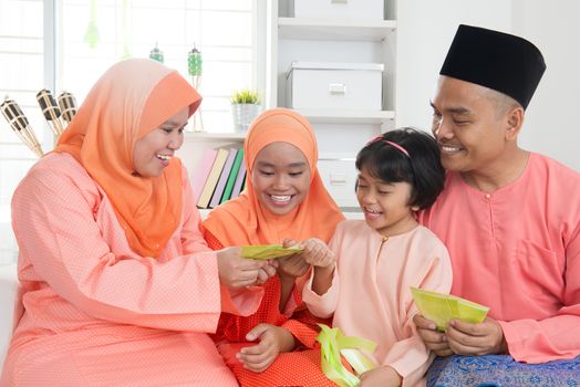 Woman giving green packet to the girls during hari raya. Malay or Malaysian family lifestyle at home.