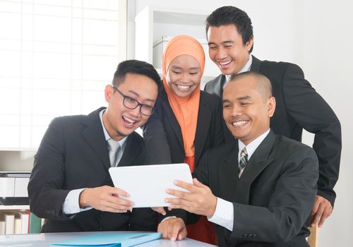 Group of Malaysian businesspeople meeting or having discussion on desk inside office room.