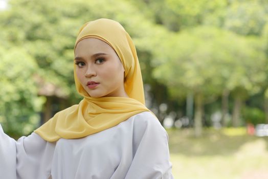 Portrait of cute Muslim girl in hijab, smiling at outdoor.