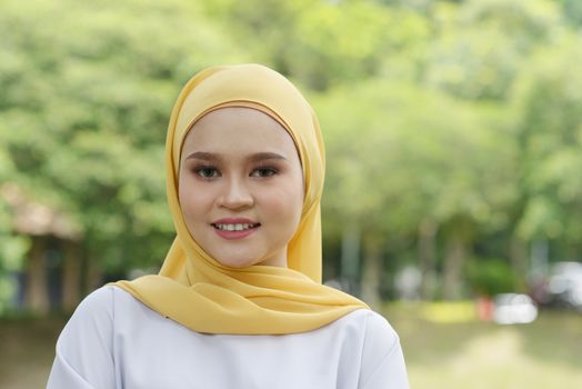Portrait of cheerful Muslim girl in hijab, smiling at outdoor.