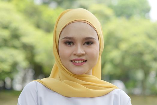 Portrait of cheerful Muslim girl in hijab, smiling at outdoor.