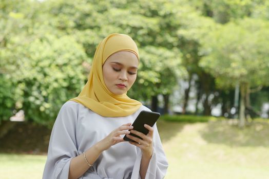 Muslim woman looking at mobile phone, negative emotions, phishing scams concept.