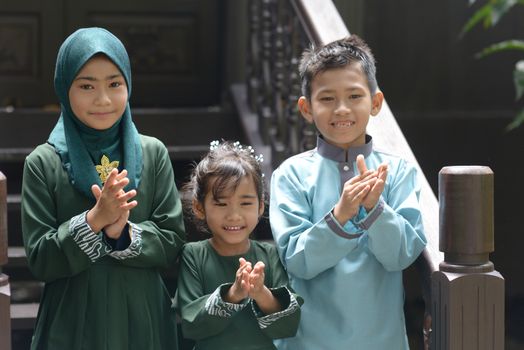 Muslim children clapping hands, Hari Raya Eid Al-Fitr concept. 