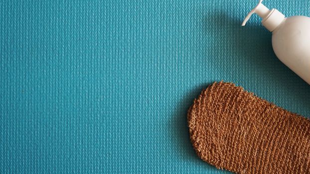 Lotion, shower sponge on a blue background. Healthy and beautiful skin concept.