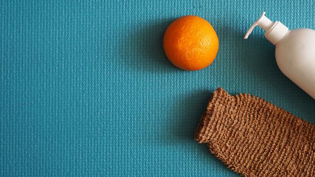 Lotion and orange fruit - anti-cellulite concept on a blue background