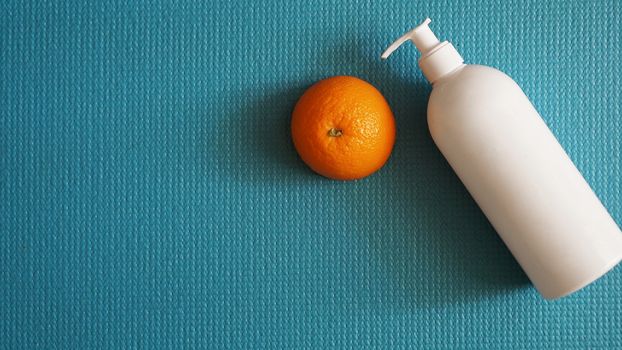 Lotion and orange fruit - anti-cellulite concept on a blue background