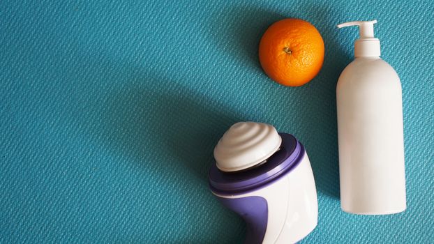 Electric massager for cellulite. Lotion, orange and anti-cellulite massage massager on a blue background