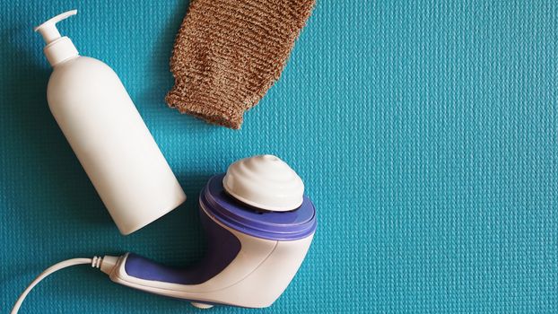 Lotion and anti-cellulite massager on a blue background. Healthy and beautiful skin concept.