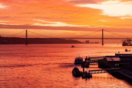 Sunset over the Tagus River off the Lisbon waterfront in Portugal. In the background can be seen the Ponte 25 de Abril.