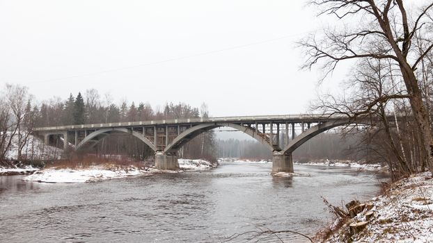 A winter view of the Gauja River and road bridge crossing it.  The bridge is near Sigulda  Latvia and is a part of the Gauja National Park.