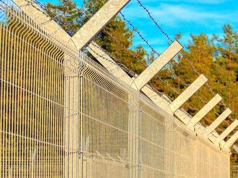 Selective focus. Security Fence In Prison. Lost freedom behind barbed wire. Old rusty barbed wire in the forest close up. Private property . Blue sky on background