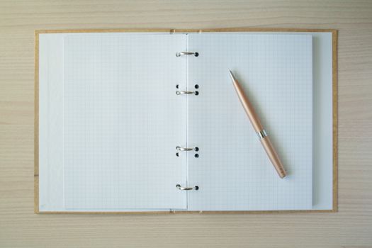 Pencil and pen with open clear notepad on wooden table, copyspace
