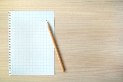 Pencil and pen with open clear notepad on wooden table, copyspace
