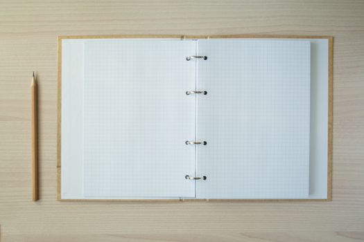 Pencil with open clear notepad on wooden table
