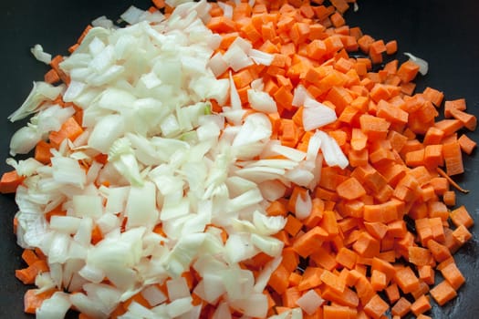 Carrot and onion cutted on black pan background