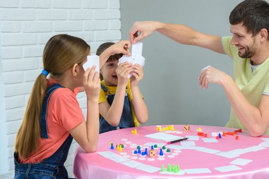 Dad draws the desired card in a board game with daughters