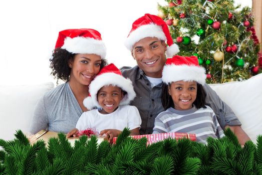 Composite image of family holding Christmas presents against digitally generated fir tree branches