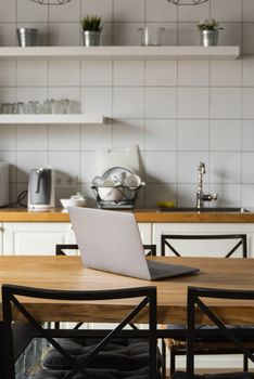 Close Up of laptop on kitchen counter with kitchen on background