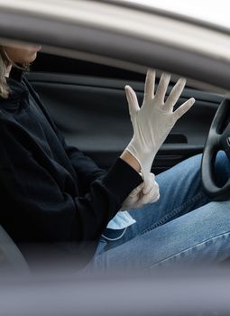 Woman in protective medical mask is wearing rubber gloves for protect himself from bacteria virus while planning to drive. Protective mask while quarantine, pandemic, covid 19, coronavirus, infection