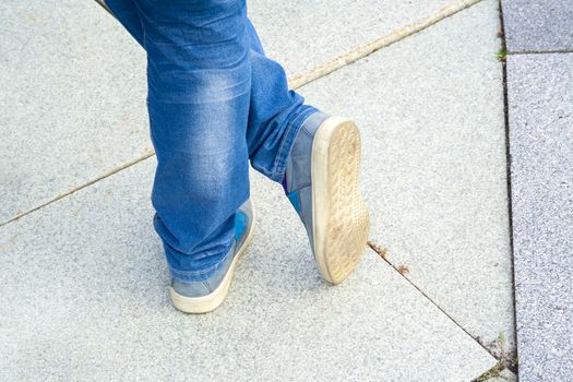 Close-up of young girl's feet and simple modern sneakers standing on cement ground. Lifestyle, relax, phisical activity