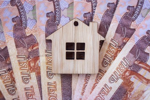 Mortgage, insurance, buying and rent, real estate business concept. Small wooden house toy on money rouble banknotes background top view