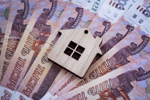 Mortgage, insurance, buying and rent, real estate business concept. Small wooden house toy on money rouble banknotes background side view