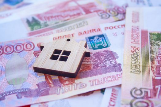 Mortgage, insurance, buying and rent, real estate business concept. Small wooden house toy on money rouble banknotes background side view