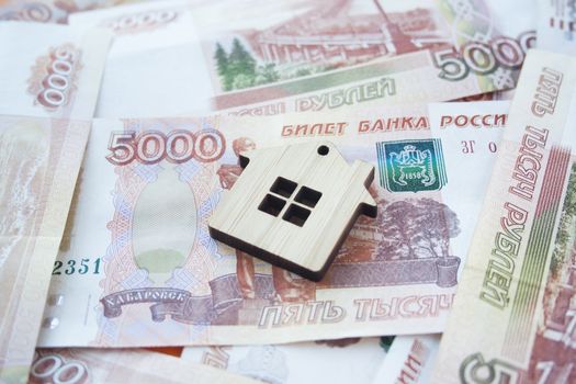 Mortgage, insurance, buying and rent, real estate business concept. Small wooden house toy on money rouble banknotes background side view