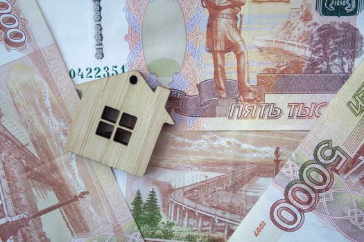 Mortgage, insurance, buying and rent, real estate business concept. Small wooden house toy on money rouble banknotes background top view