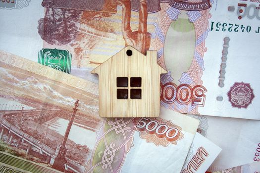 Mortgage, insurance, buying and rent, real estate business concept. Small wooden house toy on money rouble banknotes background top view