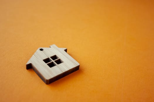 House, insurance and mortgage, buing and rent concept. Small wooden house toy on orange background side view copyspace