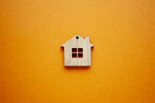 House, insurance and mortgage, buing and rent concept. Small wooden house toy on orange background top view 