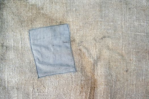 Aged vintage and weathered cloth background texture with patch. Old damaged brown rough texture 