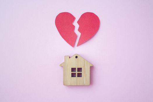 Divorce, division of property, poverty and no money concept. Wooden house with broken heart on bright pink background. Mortgage, rent, realtor