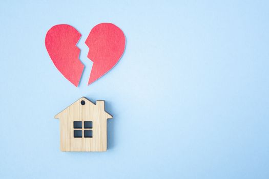 Divorce, division of property, poverty and no money concept. Wooden house with broken heart on bright blue background. Mortgage, rent, realtor