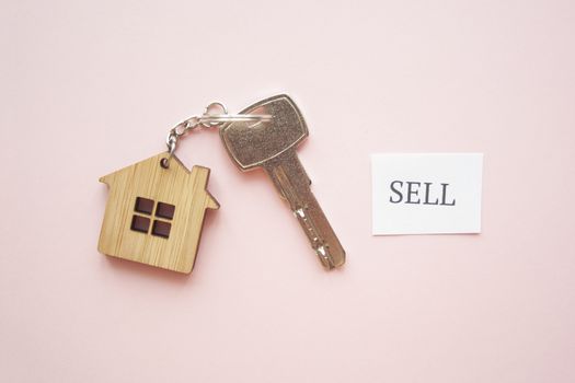 Wooden house toy and silver key on bright pink background with phrase quote Sell. Mortgage, house buy sell, investment, rent, realtor concept